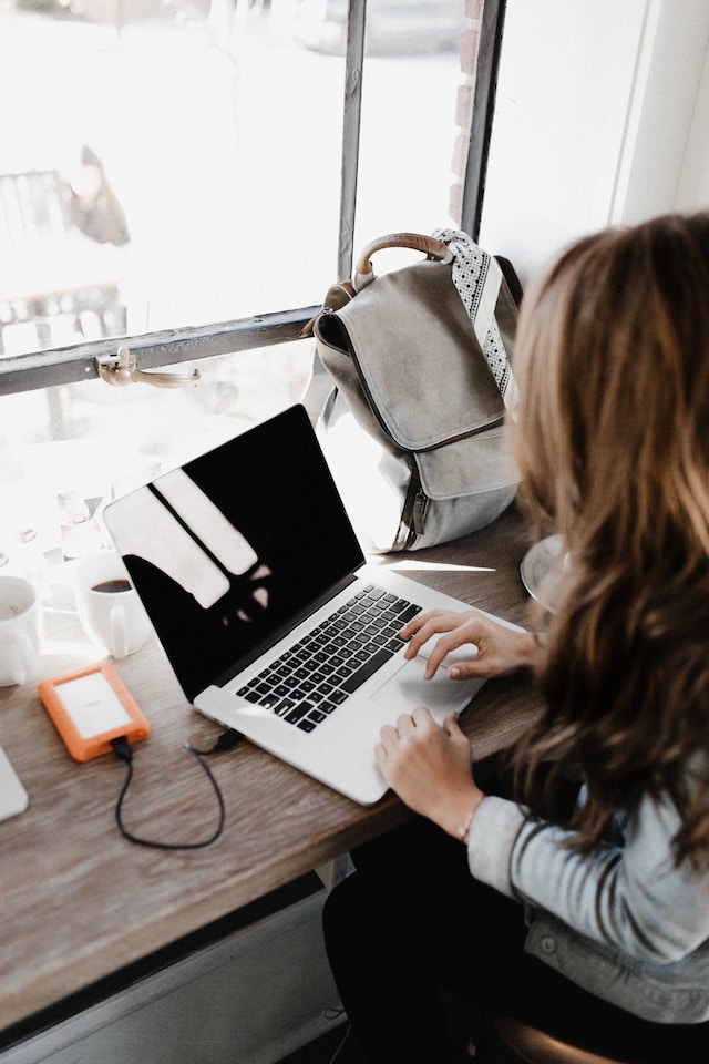 Uma mulher sentada com o seu computador portátil, a inscrever-se em Path Social para Instagram growth. 