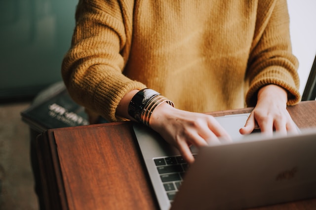 Une femme est assise à un bureau et tape sur son ordinateur portable.