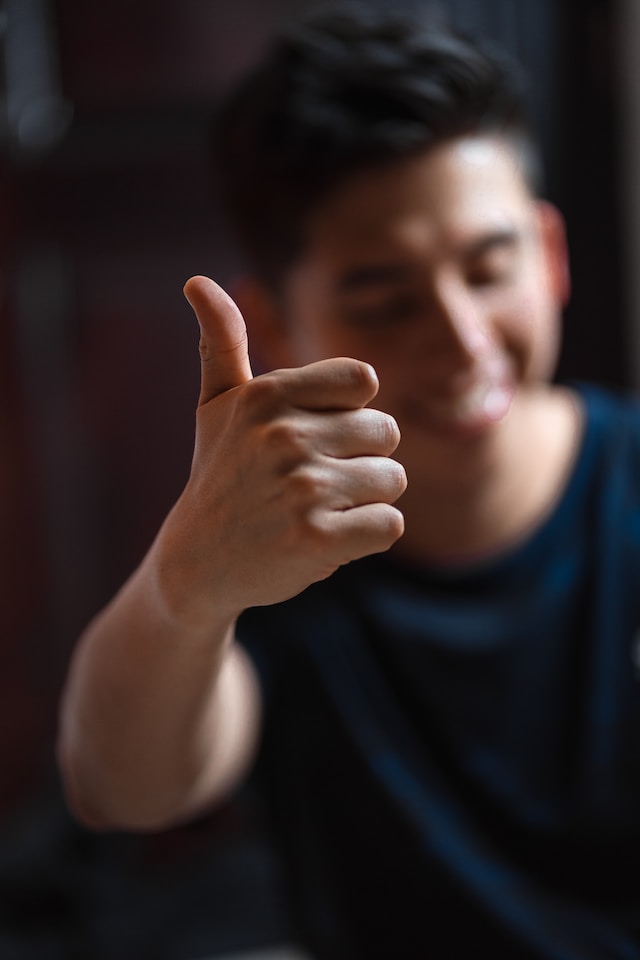 Een man met een blauw shirt geeft een duim omhoog.