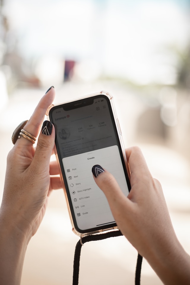 A woman holding a phone and clicking on the Instagram option. 