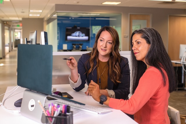 Deux femmes regardent un écran d'ordinateur tout en discutant de leur page professionnelle Instagram . 