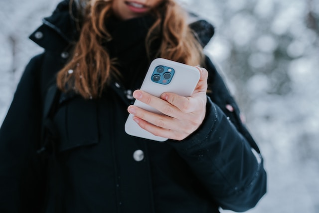 O femeie care ține în mână un iPhone și își verifică vechiul nume de utilizator pe Instagram.