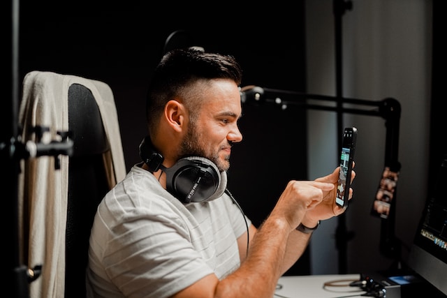 A man in a white shirt with headphones checking his latest Instagram reel updates.