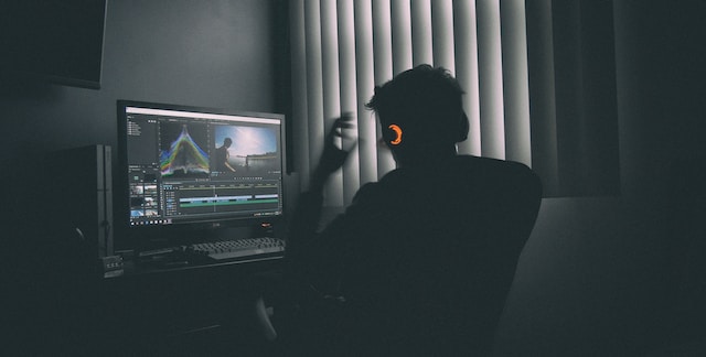 A man listening to music with headphones while editing a video.