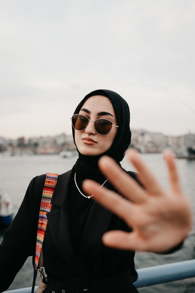 A woman standing next to a body of water while taking a picture for her Instagram story.