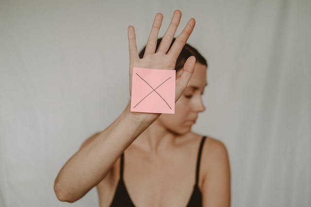 A woman holds a sticky note with a cross sign to restrict someone. 