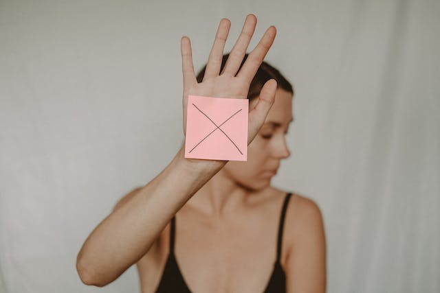 Une femme tient une note autocollante avec un signe de croix pour restreindre quelqu'un. 