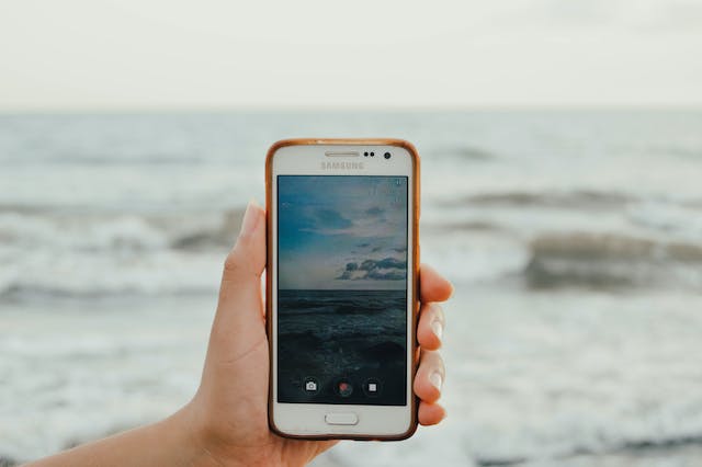 Qualcuno che registra un video dei suoi viaggi in spiaggia usando il suo telefono Android.