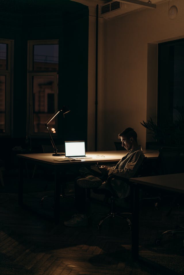 A man is sitting under the lamp light using Instagram on his phone.