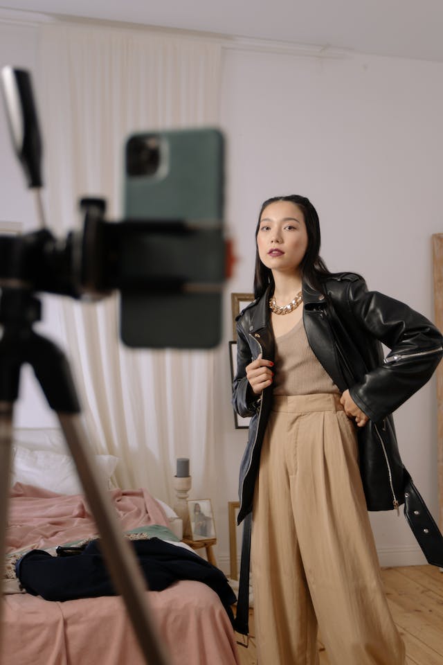 Une femme prenant une photo de sa "tenue du jour" à l'aide de l'appareil photo de son téléphone et d'un trépied.