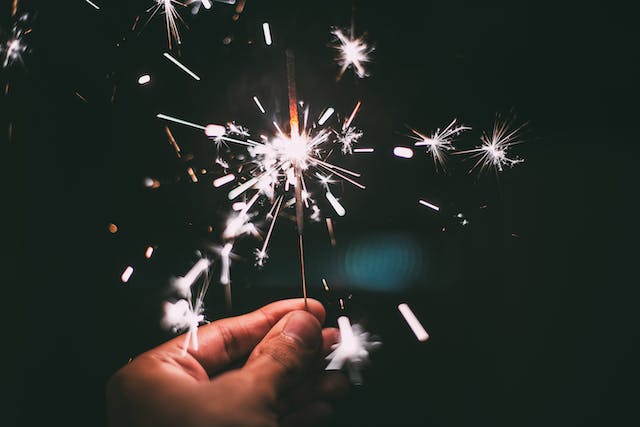 A person holding a lit-up sparkler to celebrate New Year’s Eve.