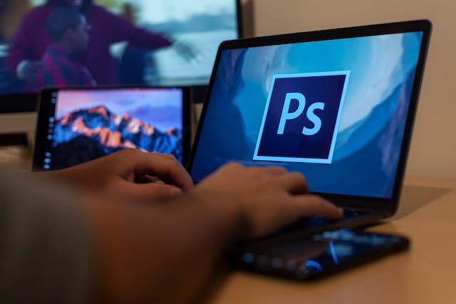 O persoană care deschide Photoshop pe laptop pentru a-și perfecționa abilitățile de editare.