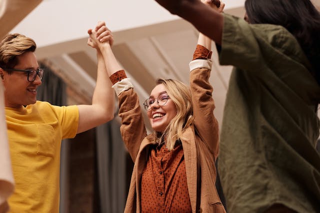 Two people hyping up their friend by holding her hands up.