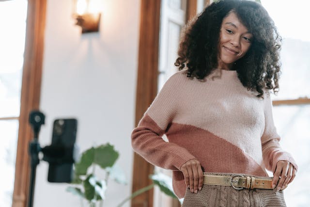 A female fashion influencer filming herself showcasing a new skirt for her followers to see.