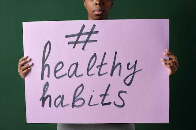 A woman holding up a poster with the hashtag #HealthyHabits.