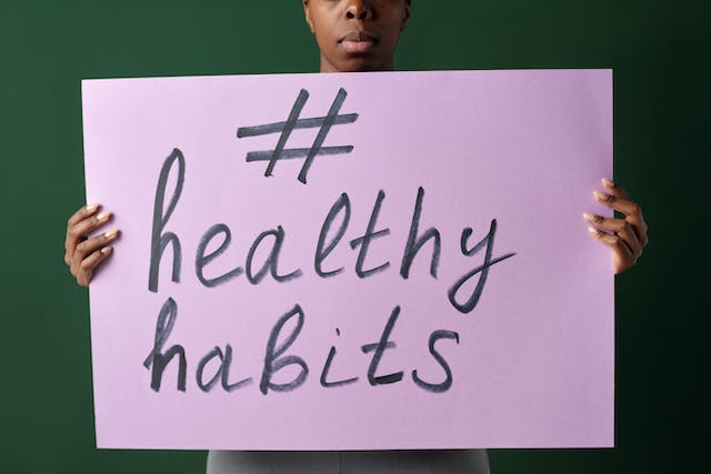 Una mujer sostiene un cartel con el hashtag #HealthyHabits.