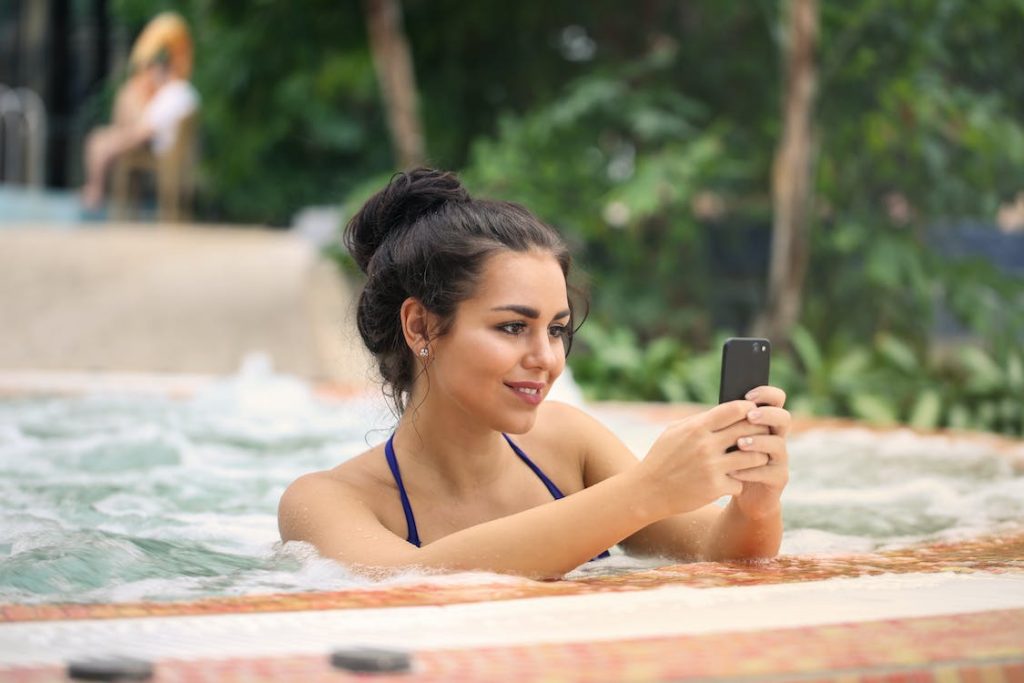 A woman is using Instagram in a jacuzzi.