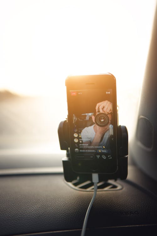 차 안에서 사진작가의 Instagram 라이브를 시청하는 사람. 