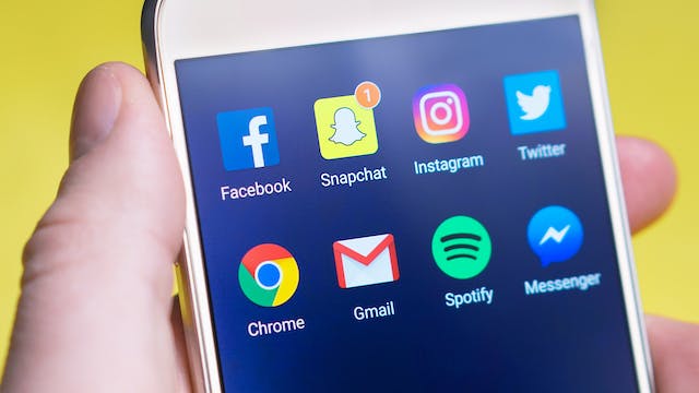 Een telefoonscherm met pictogrammen van populaire sociale apps zoals Facebook, Instagram, Snapchat en Twitter.