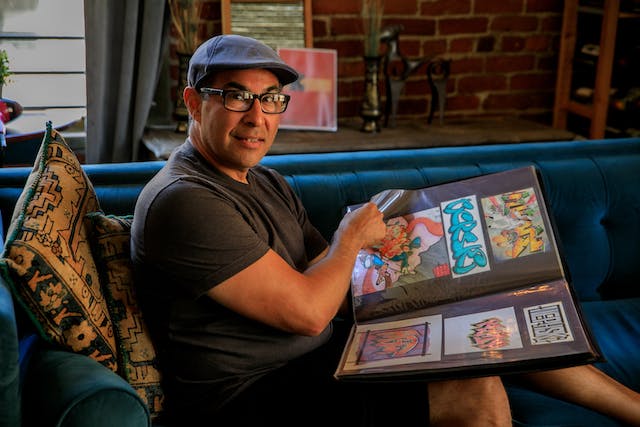 A man holding a physical graphic designer portfolio showcasing his work.