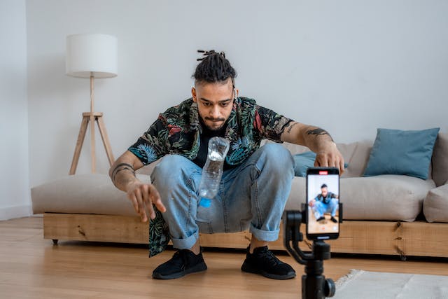 A man filming an IG Reel of him doing the water bottle flip challenge.