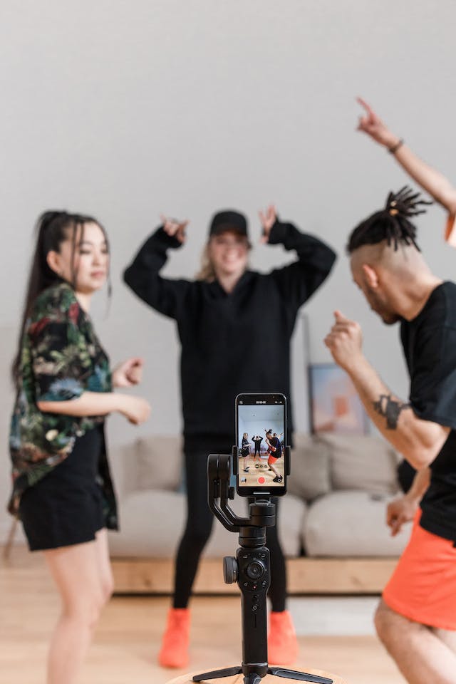 An iPhone set up on a tripod recording three friends dancing for a Reel.