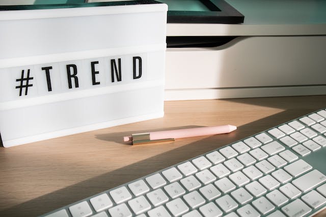 A desk with a keyboard and lightbox that has the hashtag #Trend on it.