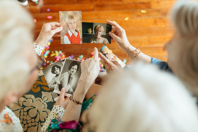 Drei Frauen, die alte Fotos von sich selbst aus ihrer Jugendzeit betrachten.