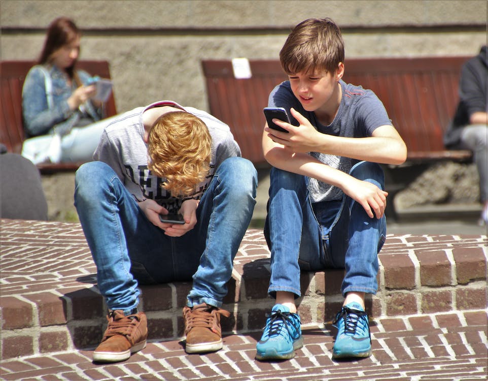 Dois adolescentes a utilizar as redes sociais nos seus smartphones.