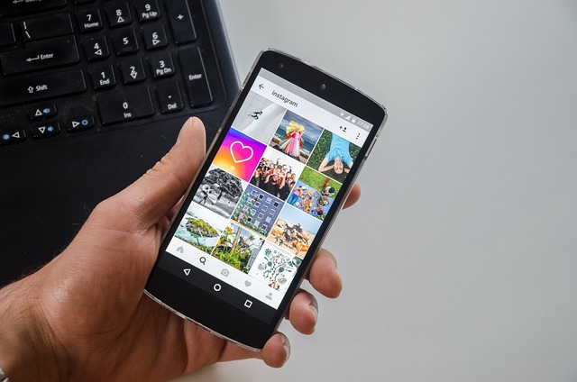 Une personne tient un smartphone noir sur lequel est ouverte l'interface Instagram .