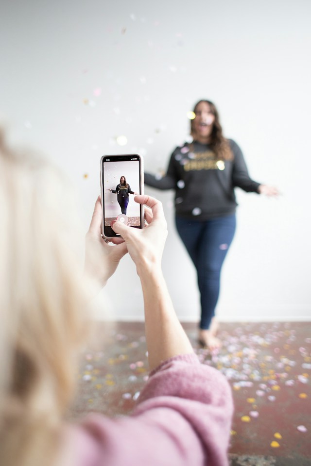 A woman taking a video of her friend doing a trendy challenge for Instagram Reels.