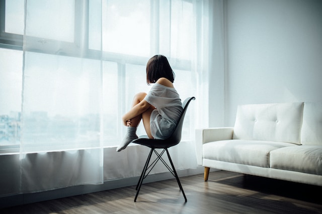 Une femme regarde tristement par la fenêtre.