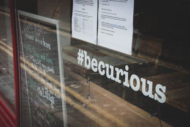 A hashtag saying “be curious” is placed on the window of a shop.