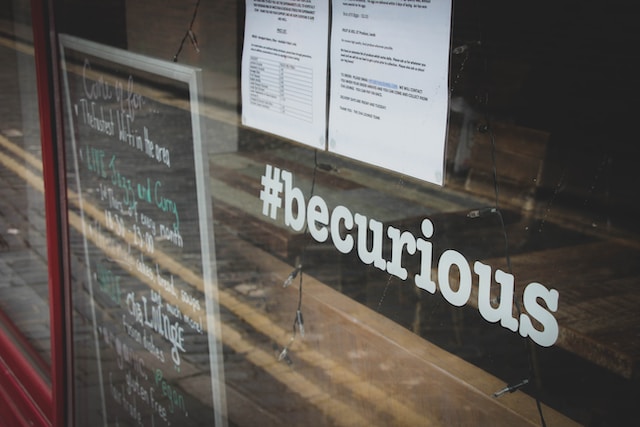 Un hashtag disant "soyez curieux" est placé sur la vitrine d'un magasin.