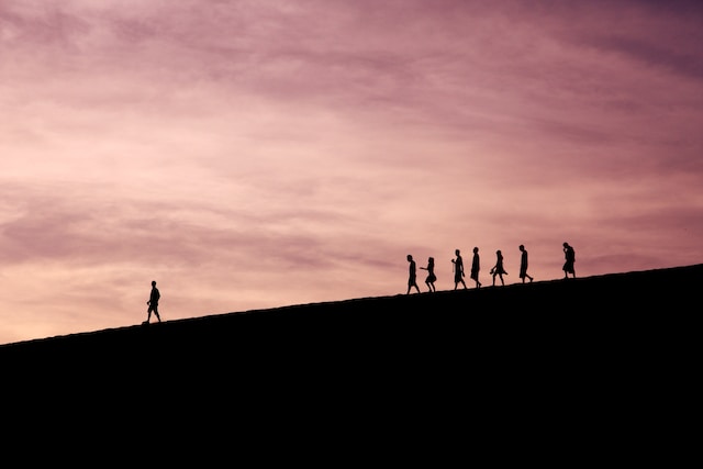 A group of people following someone down a mountain.