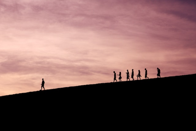 Un gruppo di persone che segue qualcuno lungo una montagna.