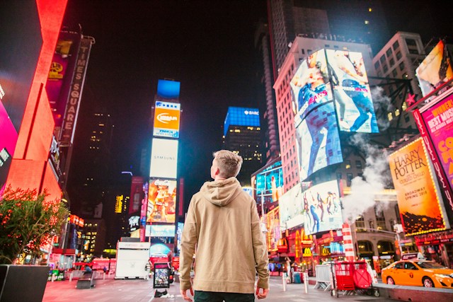 Ein Mann umgeben von Werbung am Times Square.