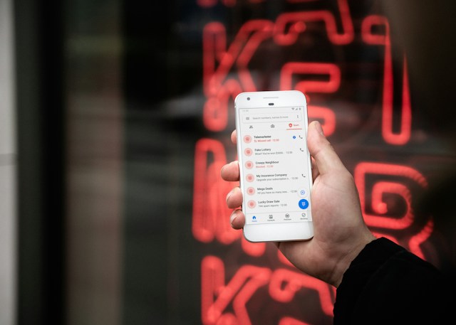 Quelqu'un qui tient un téléphone avec des tonnes de contacts spam répertoriés dans les appels manqués.