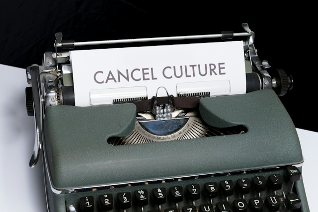 A gray typewriter printing out the words “Cancel Culture” on paper.