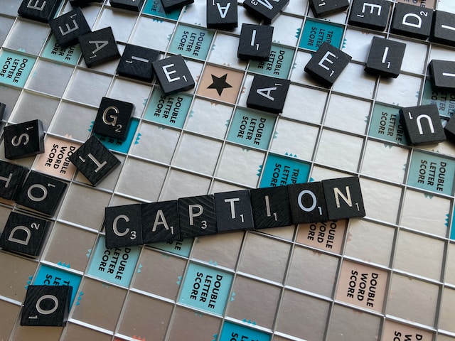 Scrabble tiles on the board game spelling out the word “CAPTION.”