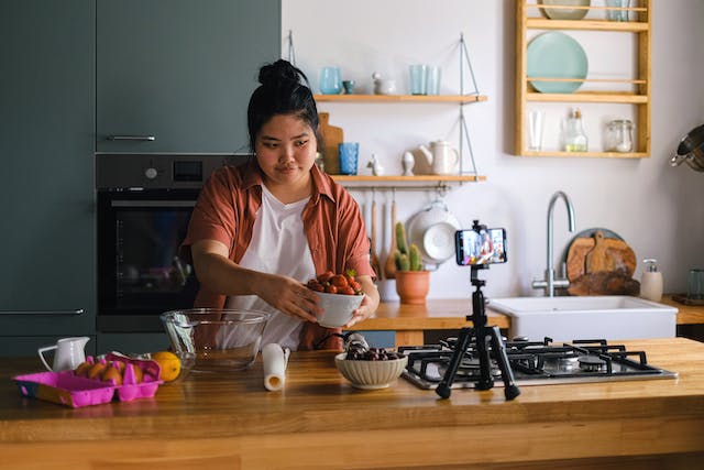 A woman taking a video of herself preparing a meal.