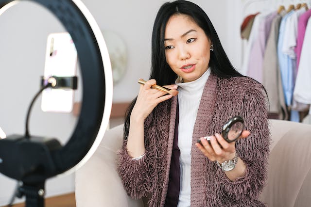 Un'influencer donna che registra un video di se stessa con la fotocamera del telefono e un treppiede.