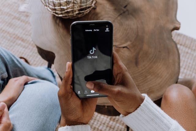 Two people sitting together and using TikTok on their phones.