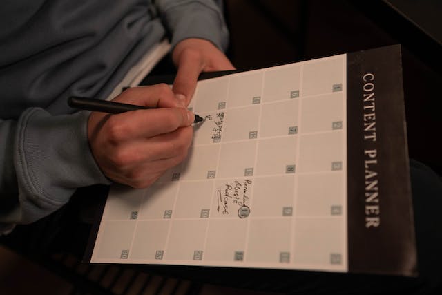 Someone writing on a content calendar to plan their Instagram post schedule.
