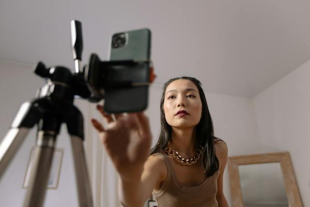 한 여성이 스마트폰과 삼각대를 이용해 온라인 챌린지 영상을 촬영하려고 합니다.