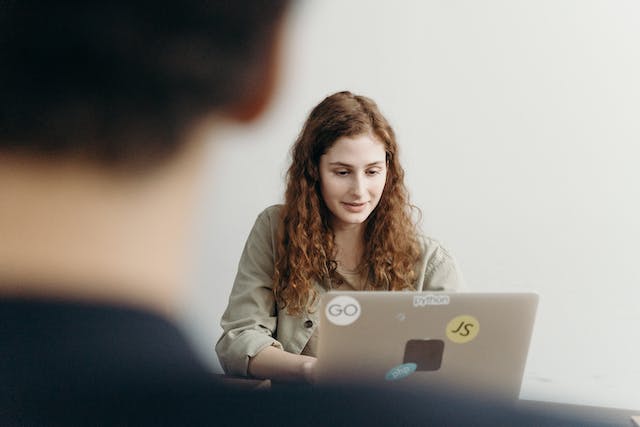 Uma mulher utiliza o seu computador portátil para procurar plataformas de marketing.