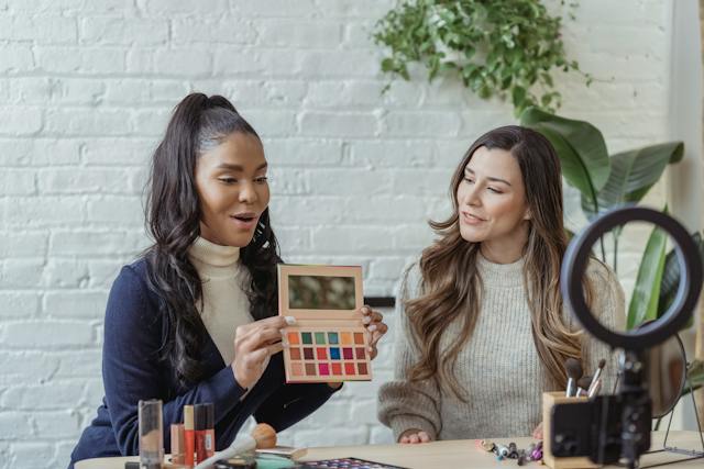 Duas influenciadoras de beleza a filmar uma boa crítica de uma paleta de sombras para publicar em Instagram.