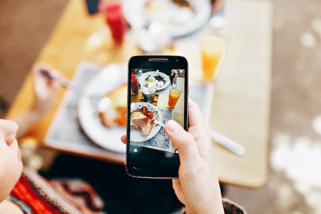 Uma pessoa que tira uma fotografia da comida que encomendou num restaurante.