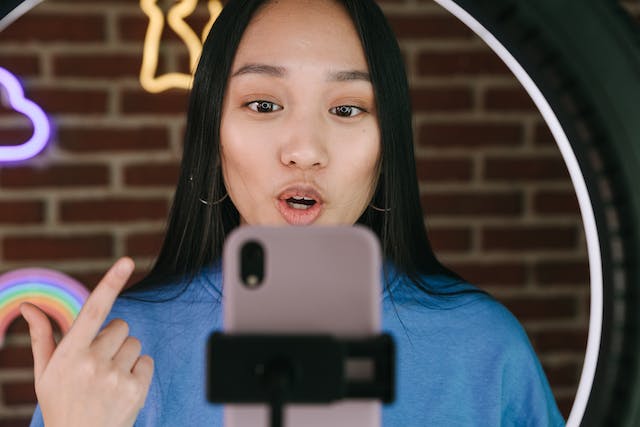 A young female influencer taking a video of herself talking to her followers.