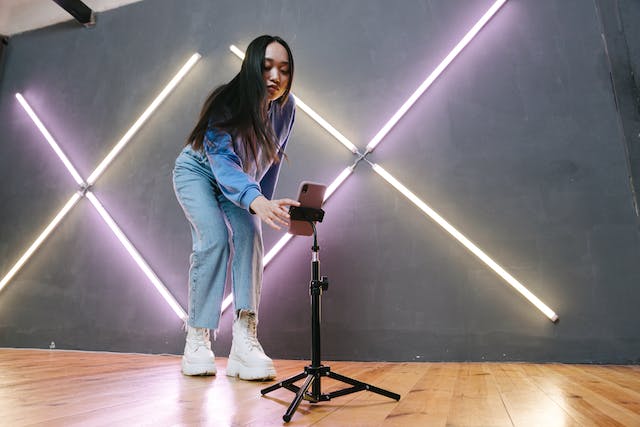 A female influencer setting up her phone camera and tripod to film an Instagram Reel.